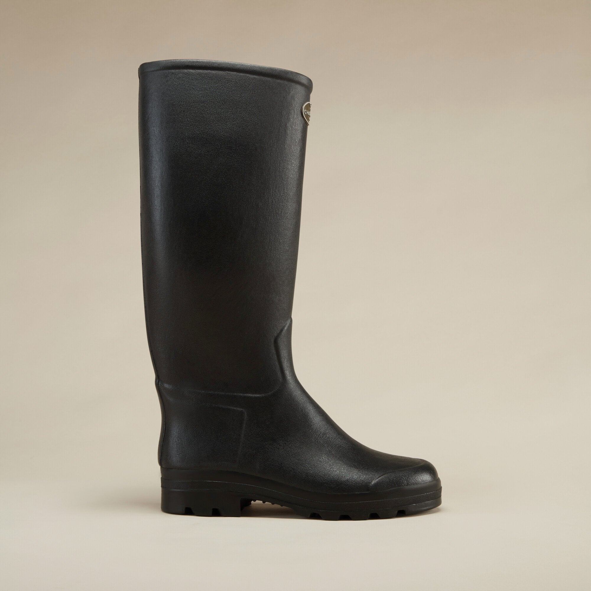 A side profile view of the Men's Saint Hubert Leather Lined Wellington Boot in Black against a beige backdrop, highlighting its tall silhouette, reinforced instep, and thick sole for outdoor traction.