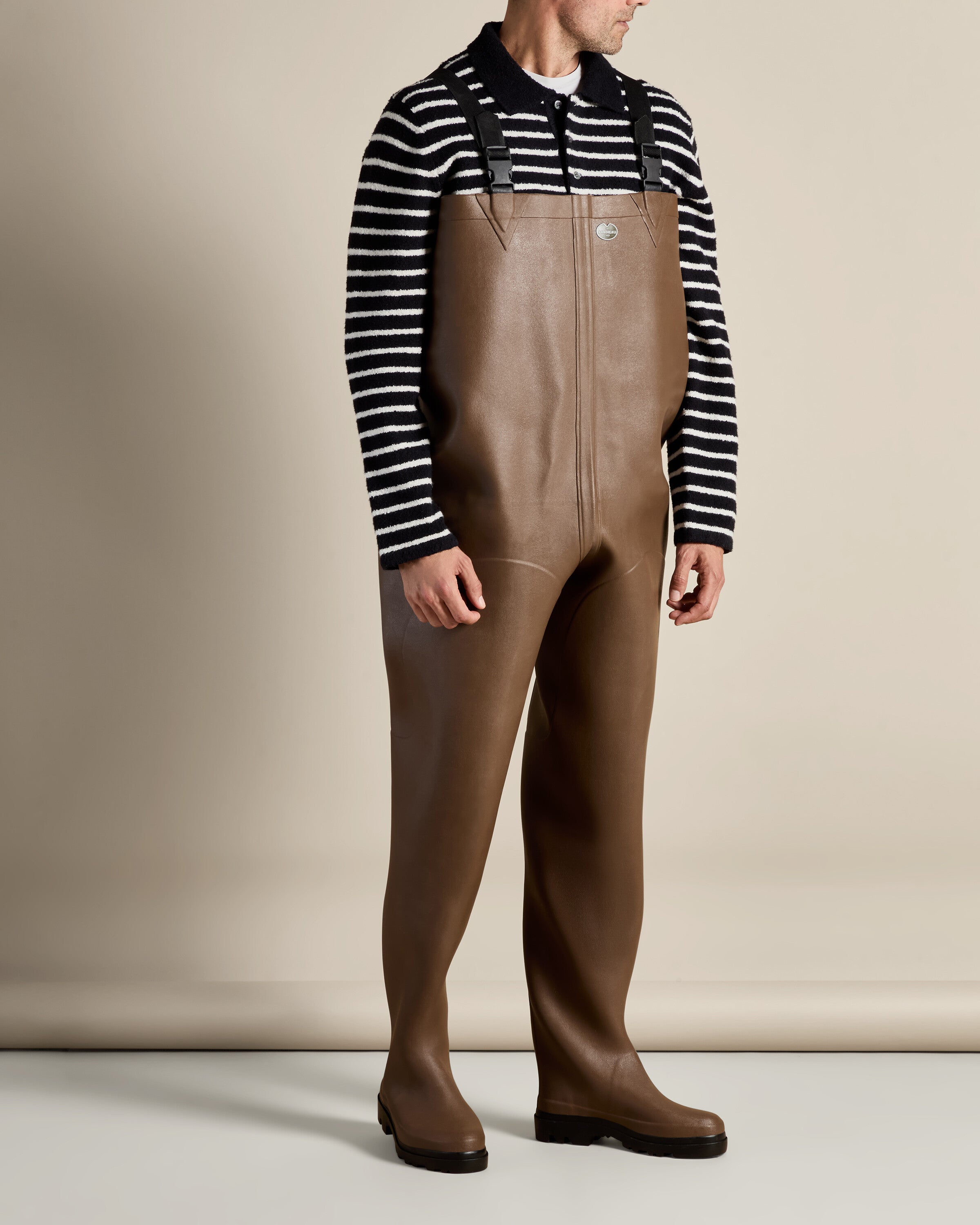 A profile shot of the model wearing the Mer Renforcé Waders in Brown, turning slightly away from the camera. This image highlights the contouring and ergonomic design of the waders as well as their sturdy base.