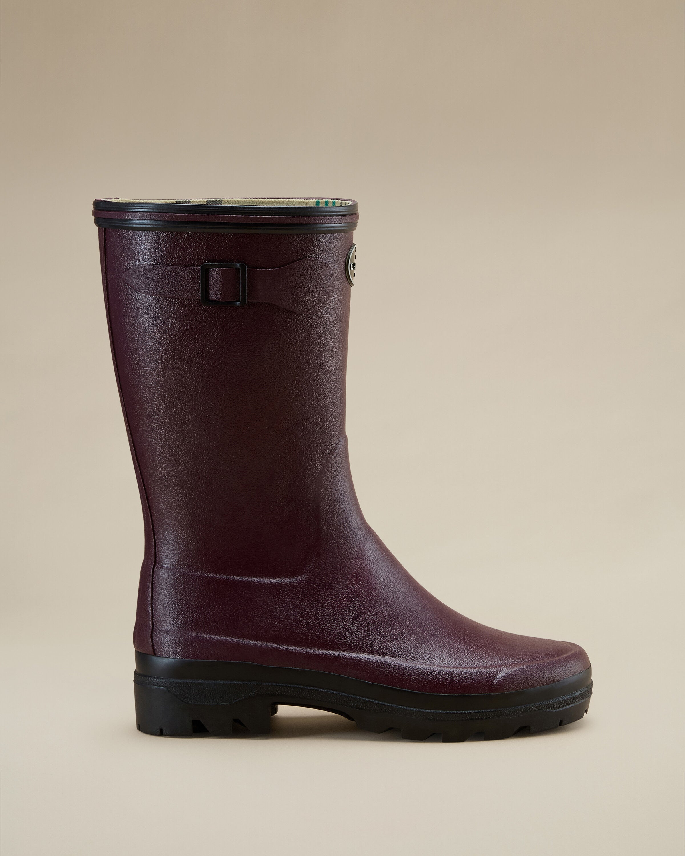 Full profile shot of the Women's Giverny Jersey Lined Bottillon in Cherry Red standing against a tan background. The boot’s mid-height shaft, logo badge, and decorative buckle strap are clearly visible, as well as the thick, grip-ready outsole.