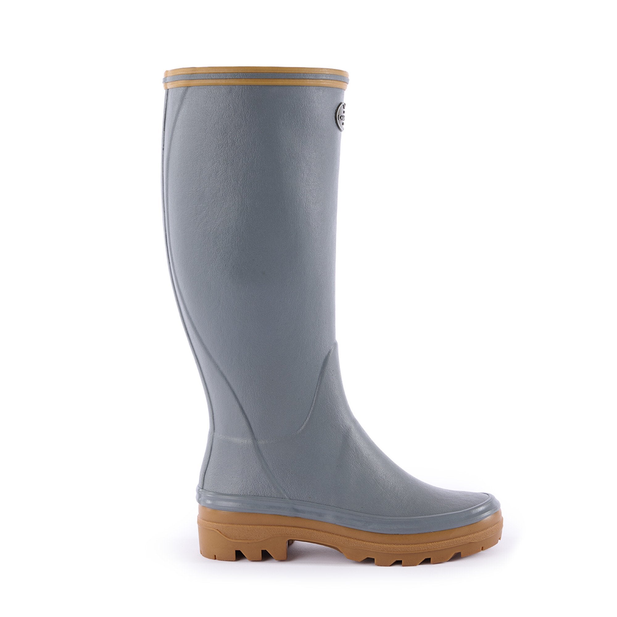A single Women's Giverny Jersey Lined Wellington Boot in Grey, shown from a left side profile view. The tall boot is light gray with a matte finish and has a tan dual-density rubber sole for enhanced grip and comfort. A tan trim outlines the top edge, and a small metallic Le Chameau logo badge is visible on the outer shaft near the top.