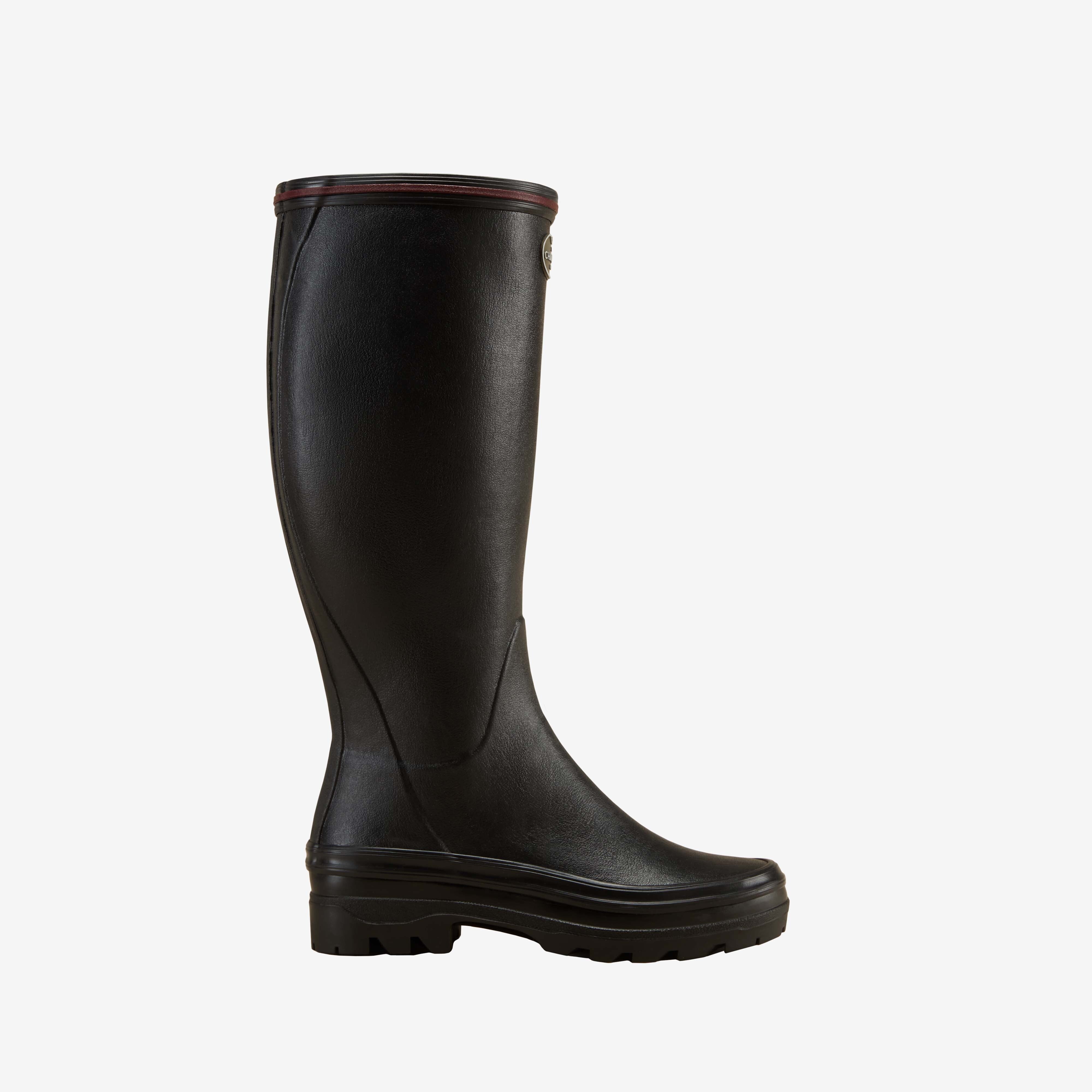Side profile of a single Women's Giverny Jersey Lined Wellington Boot in Black. Displayed on a white background, the boot features a tall shaft, rounded toe, subtle contoured paneling, and a rugged black treaded outsole. A narrow burgundy band lines the top for contrast.