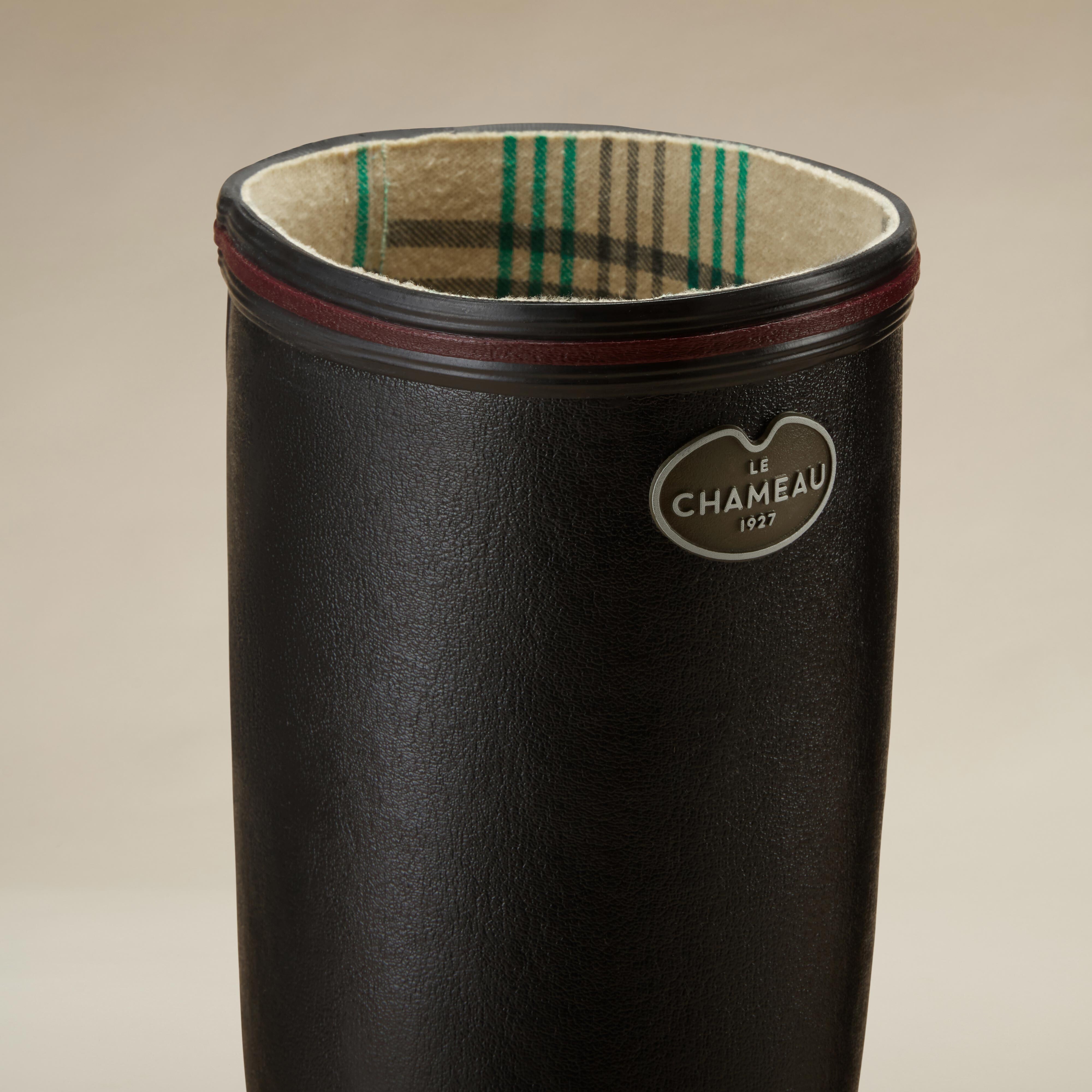 Close-up view of the top portion of the Women's Giverny Jersey Lined Wellington Boot in Black, focusing on the inner jersey lining, which features a beige plaid pattern with green and grey stripes. The burgundy rim and metal “Le Chameau 1927” badge are prominently displayed.