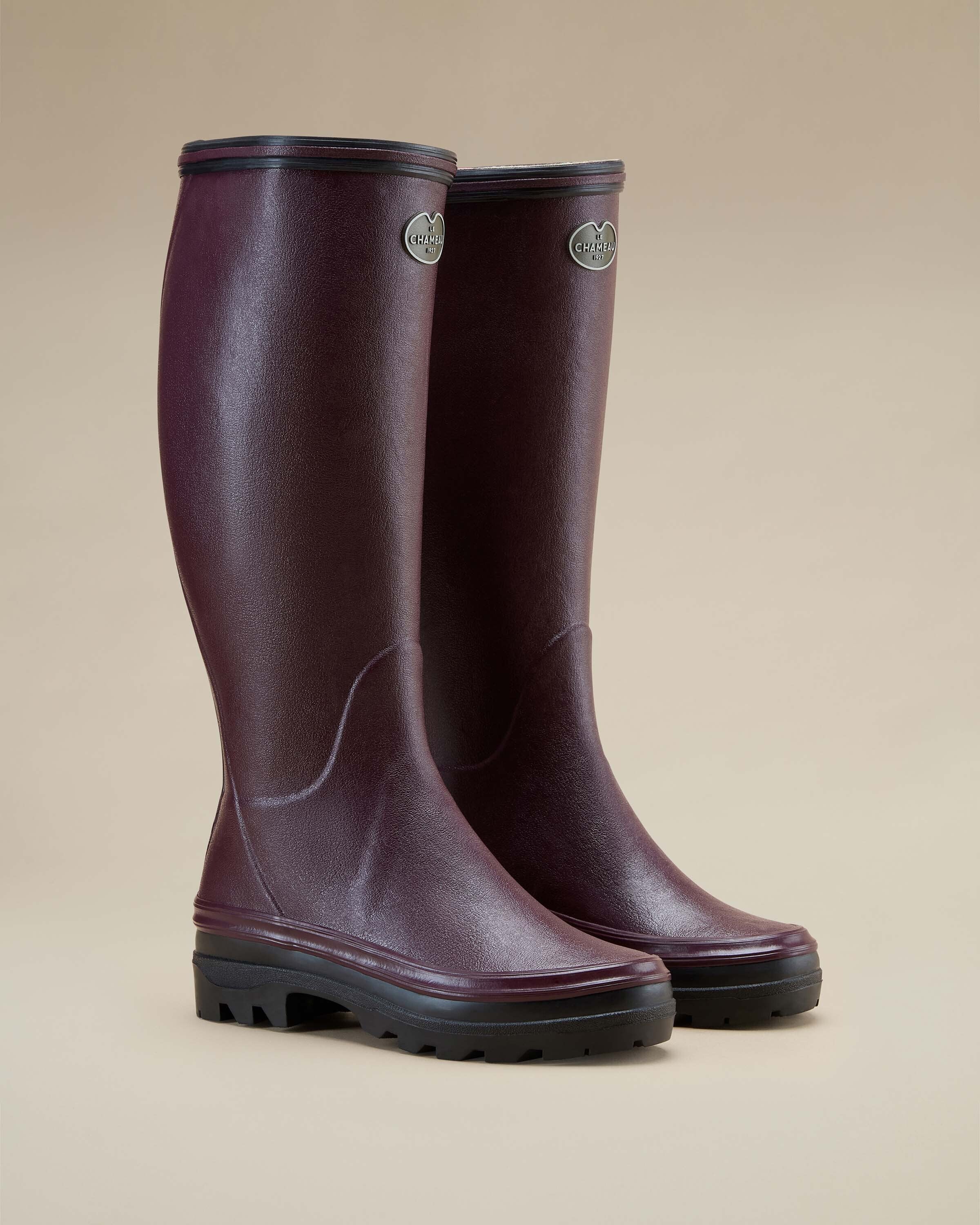 Three-quarter front angle of a pair of Women's Giverny Jersey Lined Wellington Boot in Cherry Red displayed on a light beige background. The boots stand side by side with visible Le Chameau branding on the shaft, showcasing their sleek silhouette and sturdy black outsole.