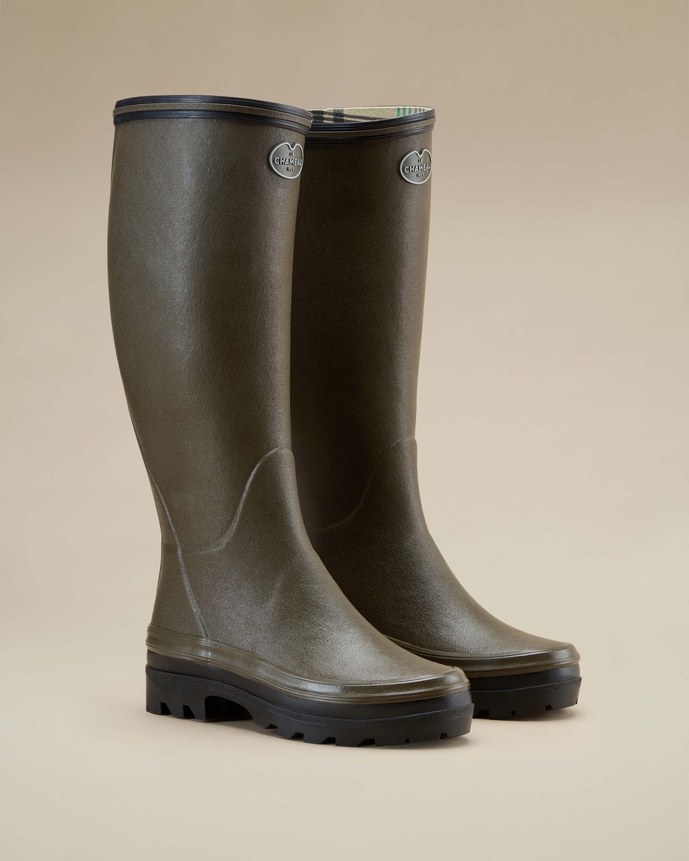 Angled view of a pair of Women's Giverny Jersey Lined Wellington Boot in Chameau Green, standing side by side and slightly turned, emphasizing the tall shaft, black soles, and contrasting black trim.