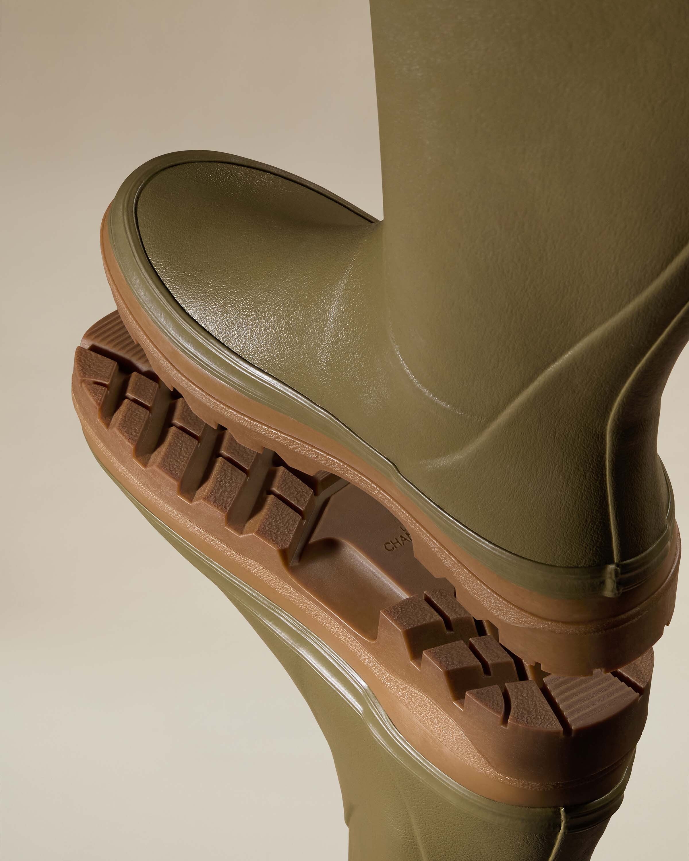 Two boots are balanced sole-to-sole to reveal the rugged, deep-lug tread pattern of the brown outsole. This close-up highlights the traction and grip features of the Women's Giverny Jersey Lined Wellington Boot in Iconic Green’s dual-density sole, showcasing both the arch and heel details.
