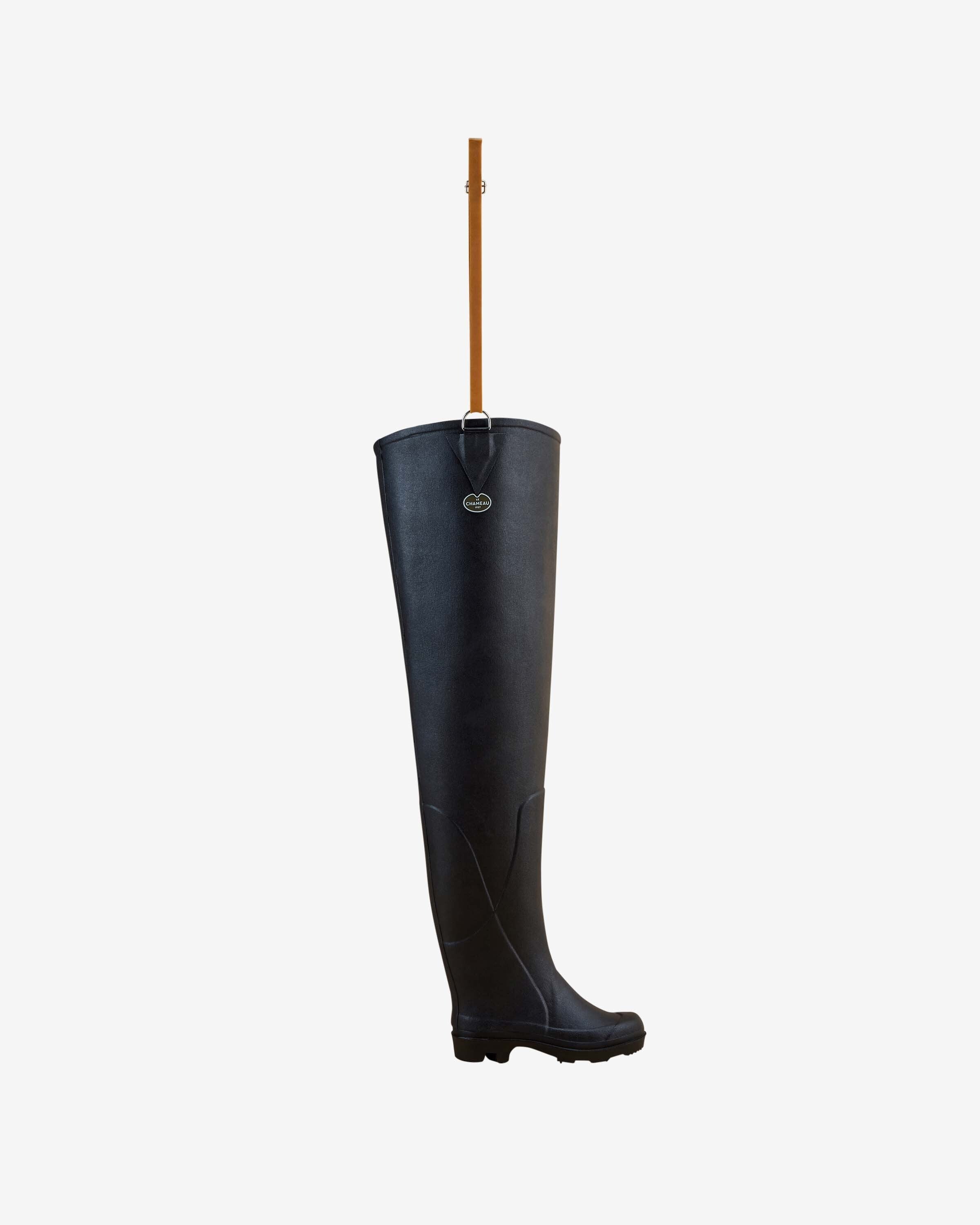 A single Women's Océane Ponti Lined Thigh Boot in Black is shown standing upright against a white background, with a brown leather strap extending upward from the top edge, designed for attachment or suspension.