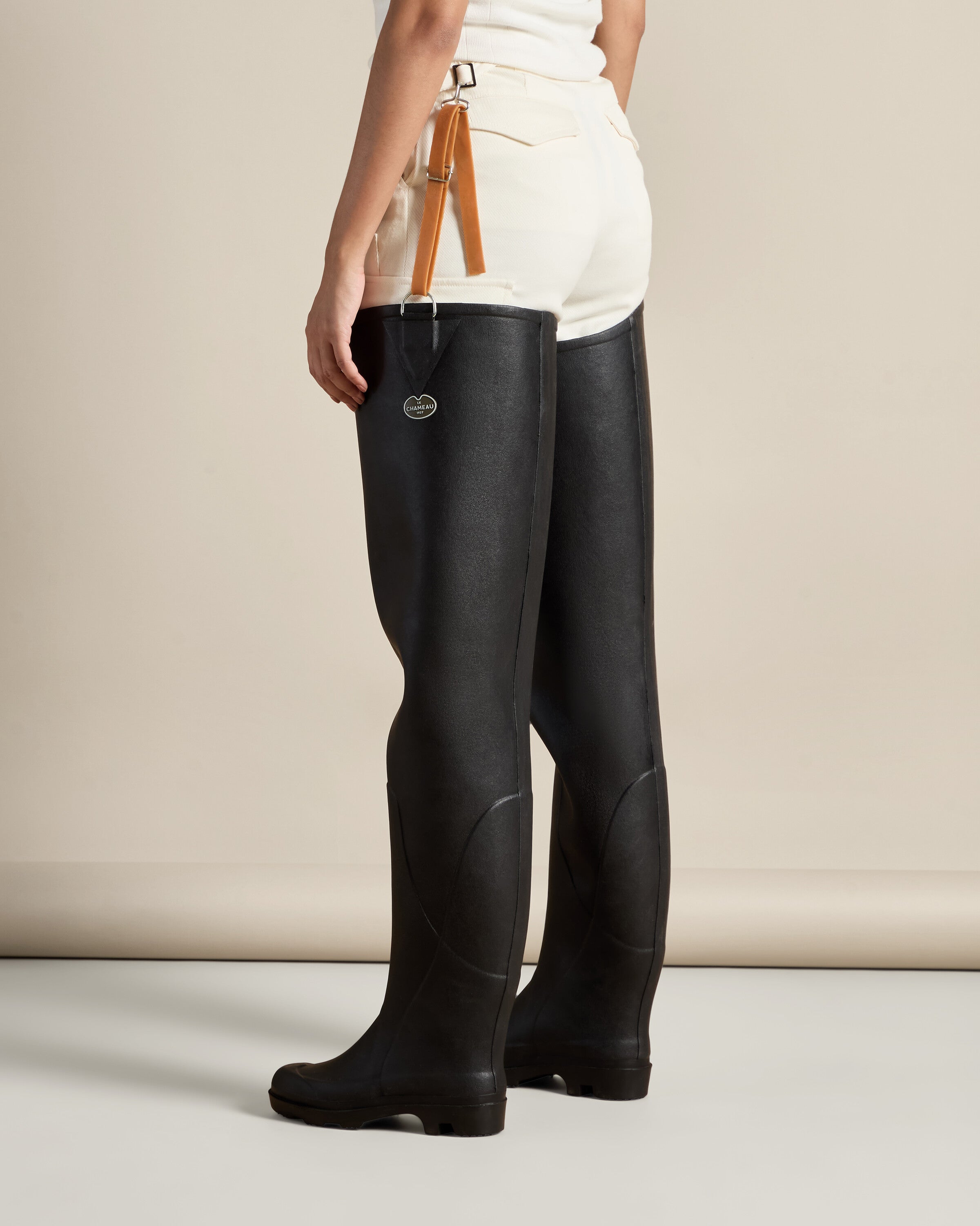 Rear angled view of the model wearing the Women's Océane Ponti Lined Thigh Boot in Black, capturing the elongated silhouette and how the straps integrate with the outfit, emphasizing comfort and function for outdoor use.