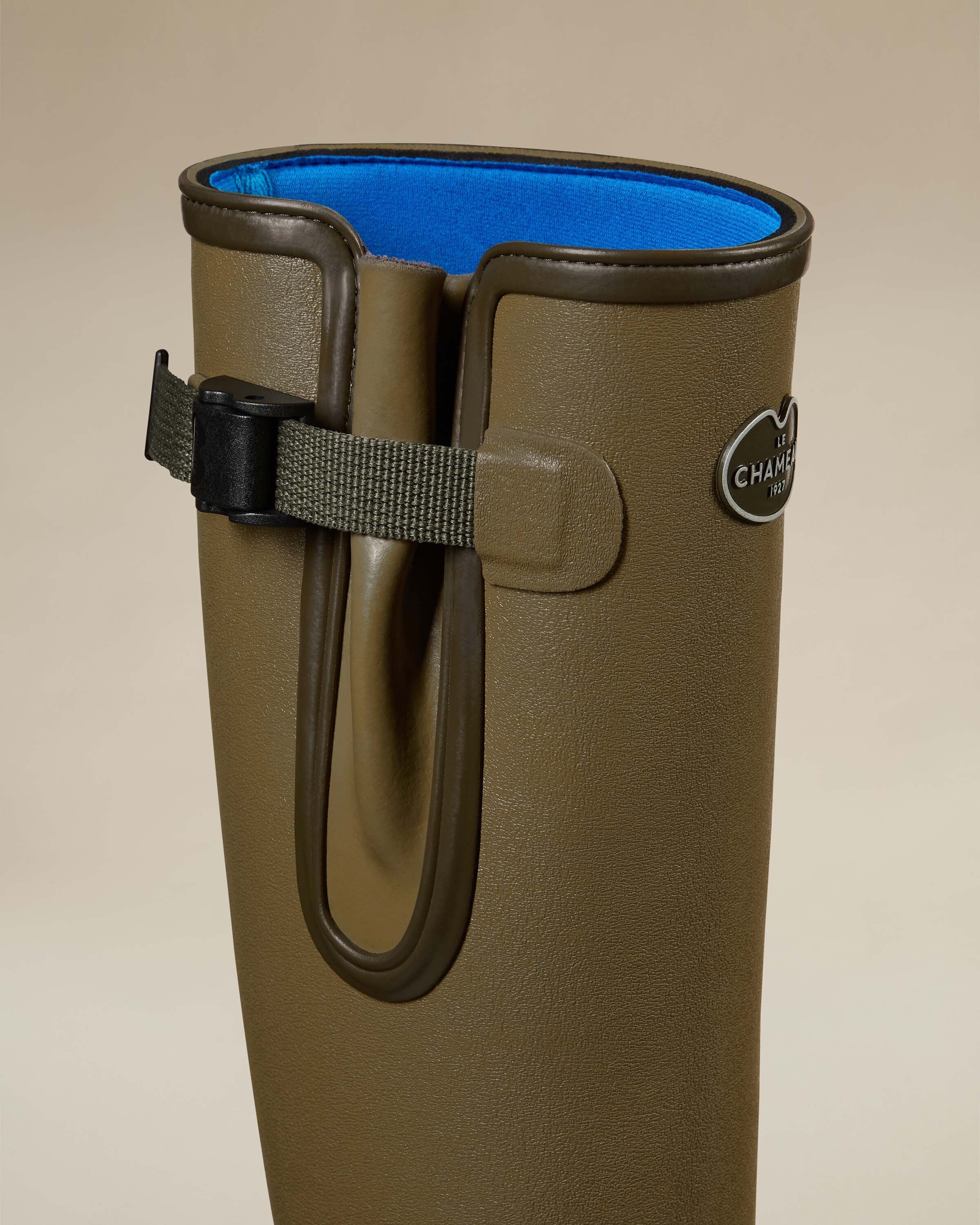 A single Women's Vierzonord Neoprene Lined Wellington Boot in Iconic Green in a dynamic three-quarter view showing the logo plaque, strap and gusset detail, and the subtle grain texture of the rubber. The image is clean and isolated on a beige backdrop, emphasizing the elegant functional design.