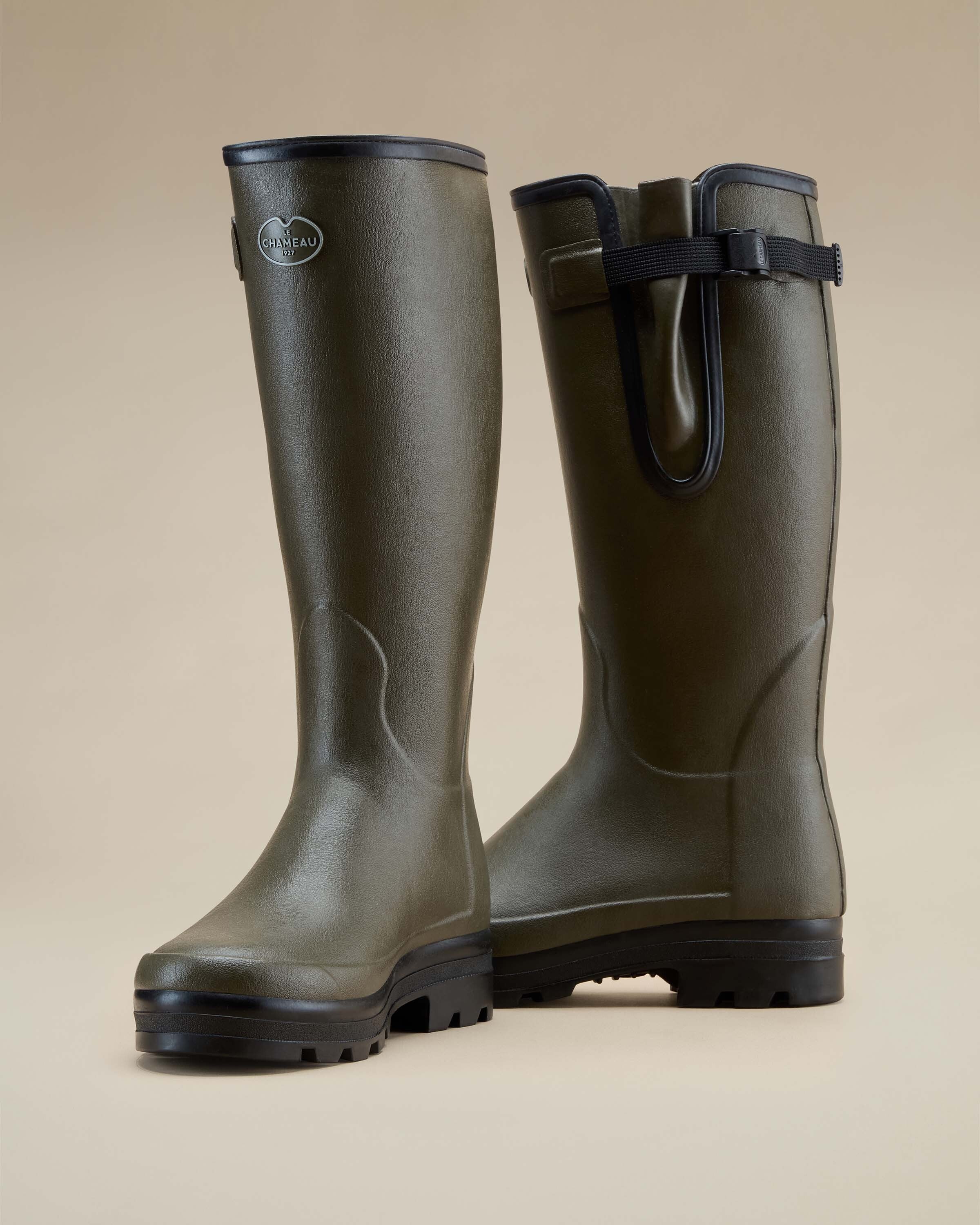Angled front view of a pair of Men's Vierzonord Neoprene Lined Wellington Boot in Chameau Green with one boot slightly forward. The photo highlights the reinforced arch contour, thick sole for shock absorption, and contrasting black outsole.