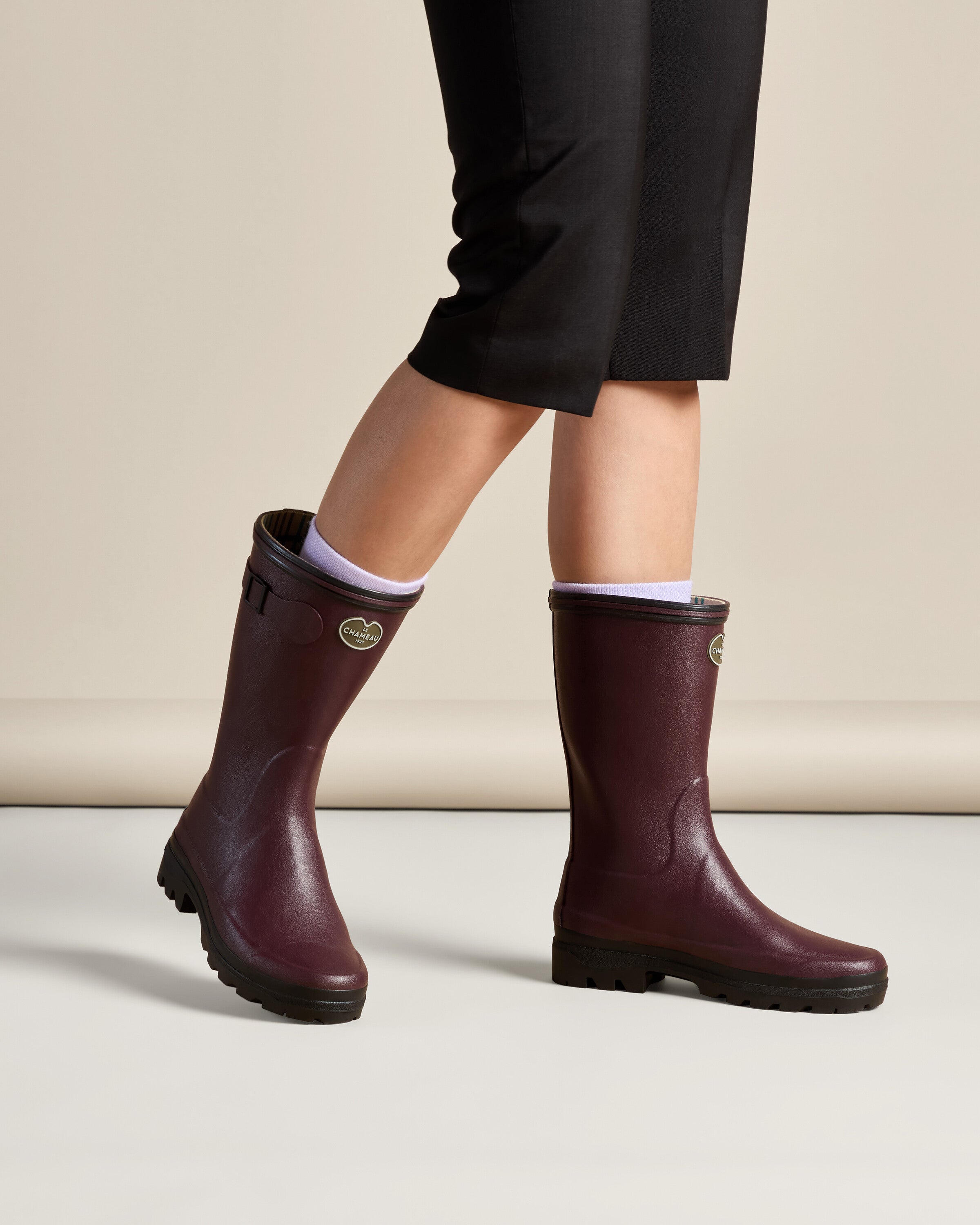 Lifestyle image of a person wearing Women's Giverny Jersey Lined Bottillon in Cherry Red with cropped black pants and white socks. The image captures the boots mid-step, demonstrating their comfortable fit and stylish utility.