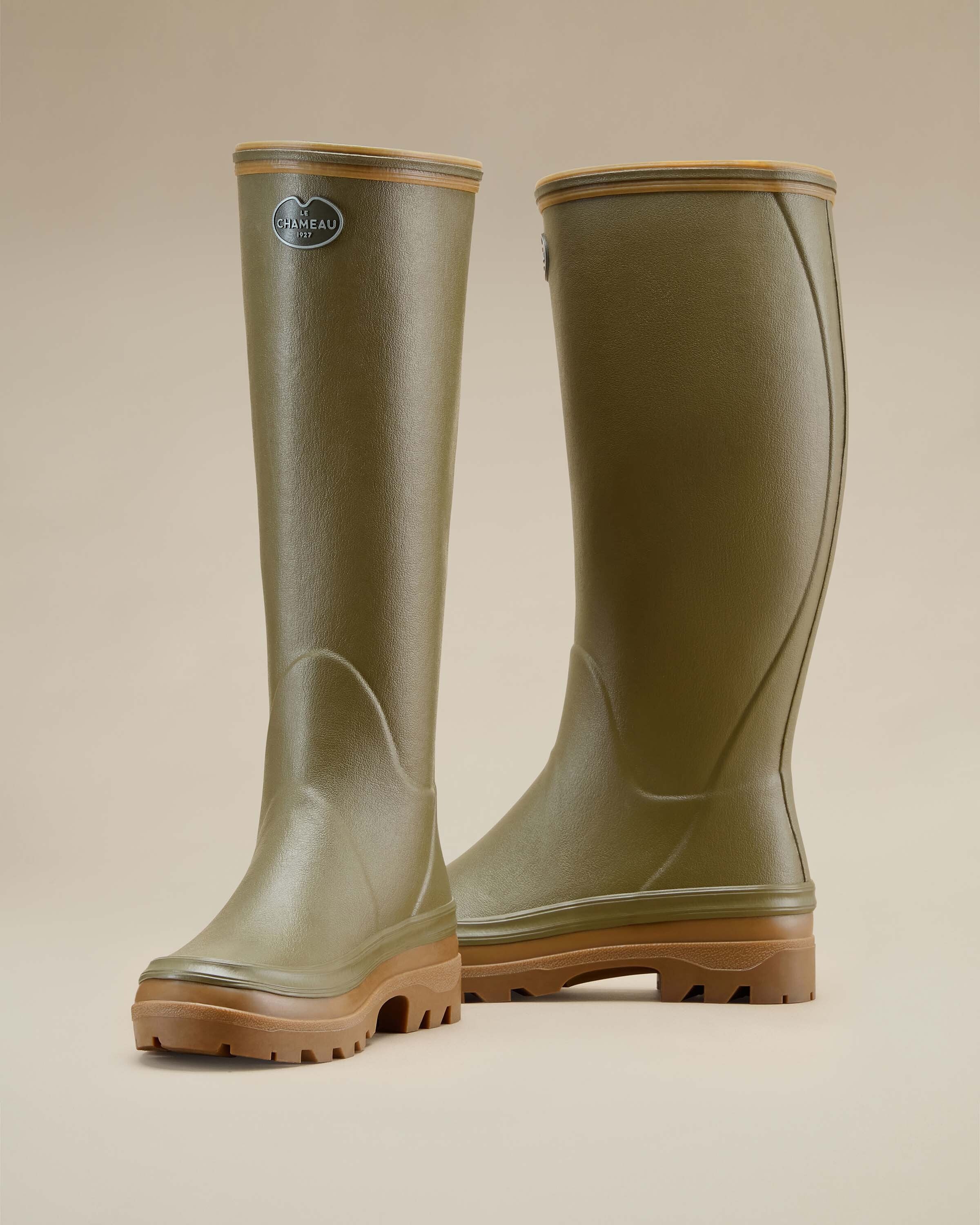 This image shows the same pair of Women's Giverny Jersey Lined Wellington Boot in Iconic Green from a three-quarter rear angle. The molded seams that shape the calf and heel areas are visible, emphasizing the supportive fit. The textured finish of the rubber and sturdy build is highlighted under soft lighting.