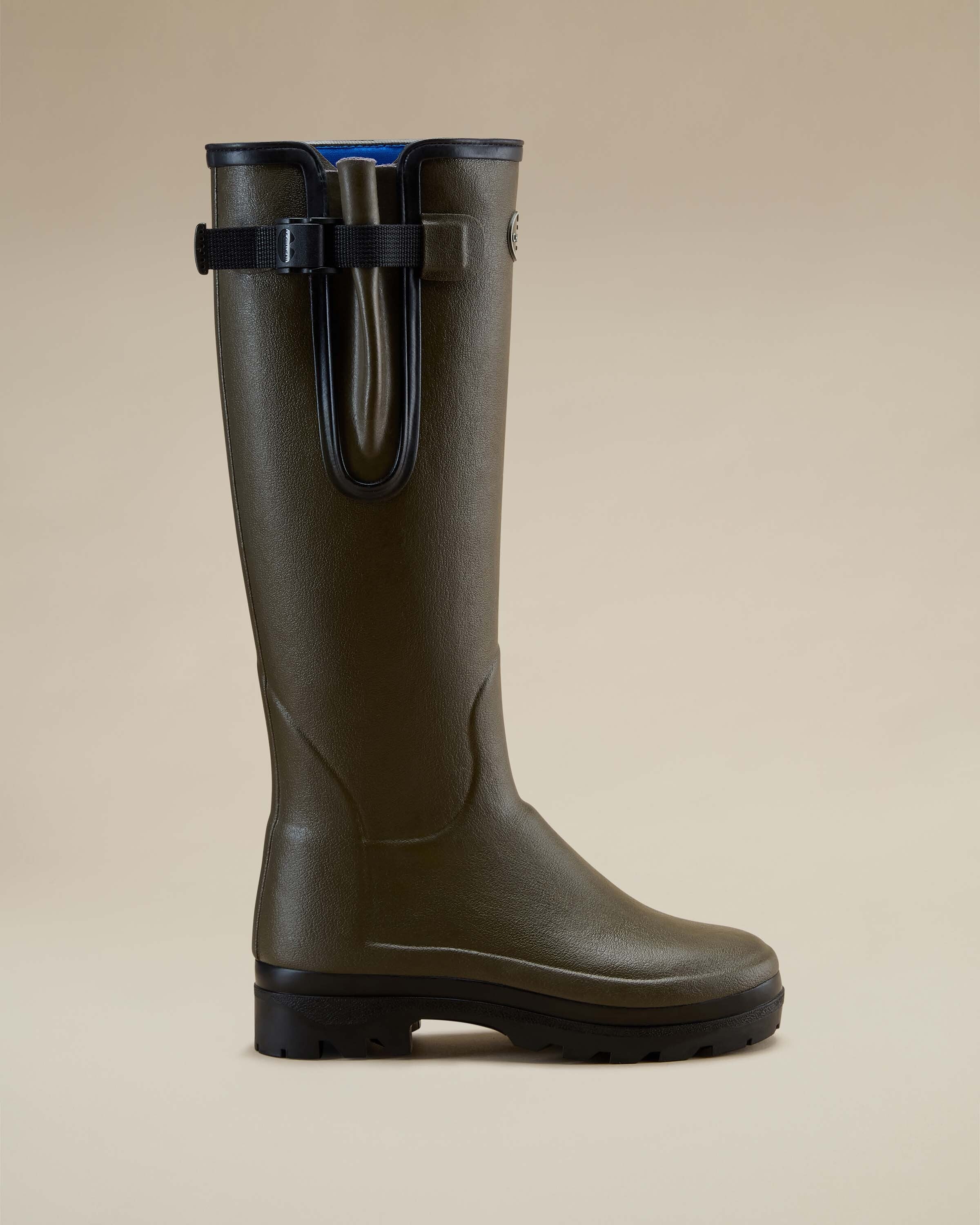 A side profile product image of a single Women's Vierzonord Neoprene Lined Wellington Boot in Chameau Green, positioned against a beige background. The boot features a durable rubber construction with a black sole and a distinctive adjustable gusset secured with a black strap near the top of the shaft. The interior lining is a bright blue neoprene, visible at the top rim. The image clearly shows the boot's ergonomic shaping and reinforced areas for durability and comfort.