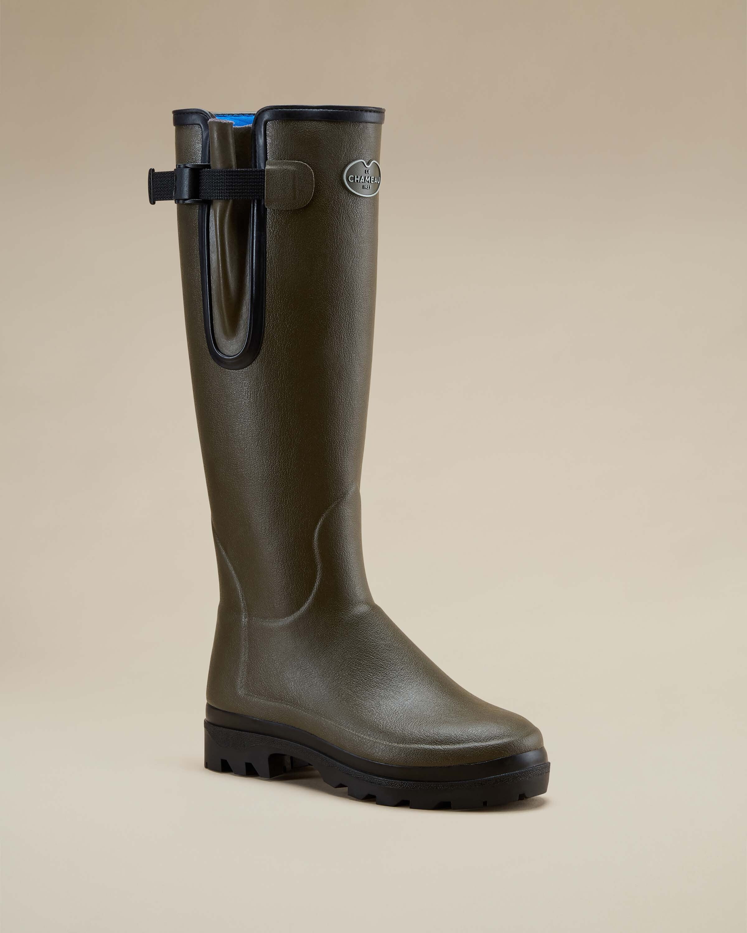Angled side-front shot of a single Women's Vierzonord Neoprene Lined Wellington Boot in Chameau Green, highlighting the sculpted ankle design and full-length shaft. The boot sits on a neutral-toned surface with a soft gradient background.